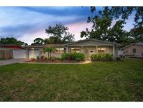 Charming single-story home with a manicured lawn, lush landscaping, and an attached garage at 1557 77Th N Ave, St Petersburg, FL 33702