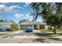 Charming single-story home featuring a well-maintained lawn and a paved driveway leading to an attached garage at 1827 Peaceful Palm St, Ruskin, FL 33570