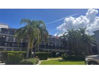 A condo building with palm trees and beautiful landscaping in front on a sunny day at 326 Windrush Blvd # 103, Indian Rocks Beach, FL 33785