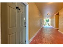 Condo hallway with yellow walls and red painted floor leading to bright outdoor area at 4207 S Dale Mabry Hwy # 2101, Tampa, FL 33611