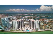 Stunning aerial view of condos with a waterfront pool, lush landscaping, and panoramic city and ocean views at 440 S Gulfview Blvd # 701, Clearwater Beach, FL 33767