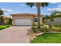 Charming single-story home with a well-manicured lawn, brick driveway, and lush tropical landscaping at 5103 Shady Stone Pl, Wimauma, FL 33598