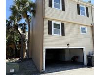 Beige townhouse showcasing a two-car garage with traditional dark brown shutters and palm tree views at 5423 Sweetwater Terrace Cir, Tampa, FL 33634