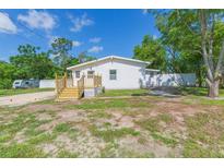 Quaint single-story home with a new deck and white siding nestled among mature trees at 9445 Cardy St, New Port Richey, FL 34654