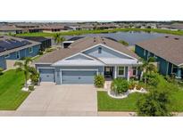 Charming single-story home with lush landscaping, a two-car garage, and a serene waterfront view at 11714 Tetrafin Dr, Riverview, FL 33579