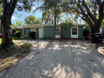 Quaint single-story home with a concrete driveway and mature trees providing shade in the front yard at 1511 Lynn Ave, Clearwater, FL 33755