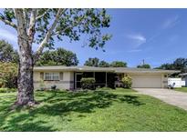 Charming single-story home featuring a well-manicured lawn and mature shade trees at 1868 Lombardy Dr, Clearwater, FL 33755