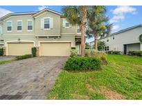 Charming townhome with lush landscaping, a brick driveway, and a two-car garage at 19272 Blue Pond Dr, Lutz, FL 33558