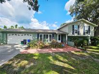 Inviting two-story home featuring lush landscaping, red brick walkway, and a two-car garage at 2014 Nancy Ave, Lutz, FL 33548