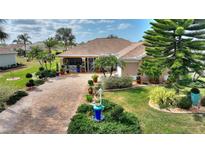 Charming home boasts lush landscaping with palm trees and a brick driveway, enhancing curb appeal at 2359 Emerald Lake Dr, Sun City Center, FL 33573