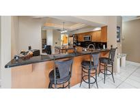 Kitchen bar with three stools and granite counters, next to wood cabinets and stainless appliances at 3037 Crest Dr, Clearwater, FL 33759