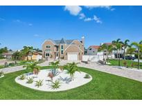 Stunning two-story home with a circular driveway, lush landscaping, and a well-manicured lawn on a bright day at 311 22Nd St, Belleair Beach, FL 33786
