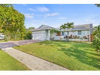 Charming single-story home with a lush green lawn, brick driveway and a beautiful mango tree in the front yard at 417 Manor Blvd, Palm Harbor, FL 34683