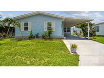 Charming light blue home with white trim, well-manicured lawn, and a covered carport at 427 Pelican S Dr, Oldsmar, FL 34677
