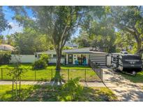 Charming single-story home with a well-maintained lawn, mature trees, and a black fence at 489 W Davis Blvd, Tampa, FL 33606