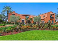 Stunning orange Spanish-style home with a lush landscaped front yard, garden and brick driveway at 501 Brightwaters Ne Blvd, St Petersburg, FL 33704