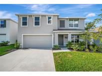 Two-story home showcasing a manicured lawn, neutral stucco, attached garage, and an inviting covered entryway at 7737 Rosewood Garden Loop, Tampa, FL 33637