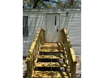 Home's front entrance featuring a new staircase and shade from trees at 9053 Bourbon St, New Port Richey, FL 34654