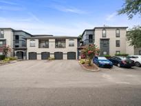 Modern apartment complex featuring private garages and ample parking, with muted two-tone color scheme at 12912 Arbor Isle Dr # 202, Temple Terrace, FL 33637