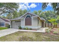 Charming single-story home features an attached garage and beautifully landscaped front yard with mature trees at 1319 Dew Bloom Rd, Valrico, FL 33594