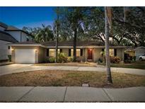 Charming single-story home with a well-manicured lawn, mature trees, and a welcoming front entrance at dusk at 3907 W Azeele St, Tampa, FL 33609