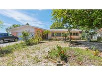 Charming single-story home featuring a quaint front yard, mature trees, and a driveway with vehicle at 4720 Coronado S Way, Gulfport, FL 33711