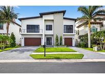 Modern two-story home boasting a manicured lawn, dual garages, and minimalist design against a clear sky at 131 Forest Hills Dr, Redington Shores, FL 33708