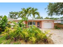 Charming single-story home with a lush front yard, palm trees, brick driveway, and a one-car garage at 1517 60Th S St, Gulfport, FL 33707
