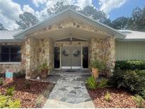 Inviting stone facade entrance with a charming walkway and well-manicured landscaping at 2215 Toniwood Ln, Palm Harbor, FL 34685