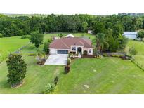 Charming single-story home with well-manicured lawn, mature trees, and a screened-in porch at 23075 Hayman Rd, Brooksville, FL 34602