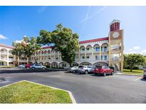 Condo building exterior featuring a beige facade, red roof, and decorative clock tower detail at 2430 Florentine Way # 40, Clearwater, FL 33763