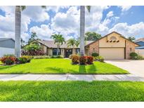 Charming home exterior with well-manicured lawn, mature landscaping, and brick-accented facade at 3437 Aspen Trl, Clearwater, FL 33761