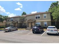 A tan two-story townhouse with parking in front and a well-maintained landscape, creating an inviting curb appeal at 36137 Lake Chase Blvd # 102, Zephyrhills, FL 33541