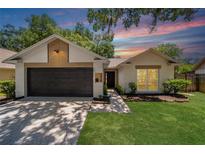 Charming home featuring a well-maintained lawn, a black garage door and neutral color scheme at 4639 Cabbage Palm Dr, Valrico, FL 33596