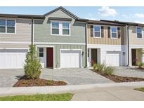Townhome exterior featuring attached garages, brick driveway, and colorful siding details at 7683 Deer Valley Circle, Tampa, FL 33635