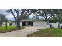 Charming home featuring a well-maintained lawn, and ample parking space with mature shade trees at 1027 Fountainhead Dr, Largo, FL 33770