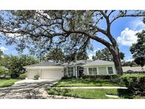 Charming single-story home featuring a well-manicured lawn, mature landscaping, and a spacious three-car garage at 11501 Norval Pl, Temple Terrace, FL 33617