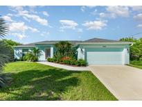 Charming single-story home featuring a manicured lawn, vibrant landscaping, and an attached two-car garage at 13116 Marathon Blvd, Port Charlotte, FL 33981