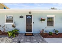 Charming front door with modern tile walkway, decorative plants and hanging flower baskets, providing great curb appeal at 1406 Nebraska Ave, Palm Harbor, FL 34683