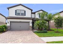 Charming two-story home showcasing a brick driveway, a two-car garage, and well-manicured landscaping at 19259 Mossy Pine Dr, Tampa, FL 33647