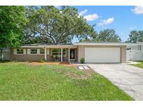 Charming single-story home with a well-manicured lawn, mature trees, and an attached two-car garage at 2353 Eastwood Dr, Clearwater, FL 33765