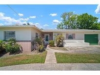 Charming single-story home with brick accents, a green garage door, and a well-manicured lawn at 2502 Tropical Shores Se Dr, St Petersburg, FL 33705