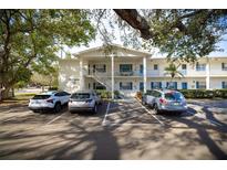 Condo building exterior with covered stairwells and mature trees creating shade for the parked cars at 500 Glennes Ln # 202, Dunedin, FL 34698