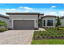 Beautiful single-story home featuring manicured landscaping, brick driveway, and neutral exterior color palette at 6072 Silver Grass Ct, Nokomis, FL 34275