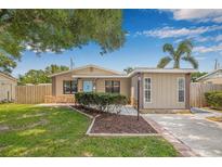 Charming single-story home with a well-manicured lawn, mature trees, and a welcoming light blue front door at 6944 80Th N Ave, Pinellas Park, FL 33781