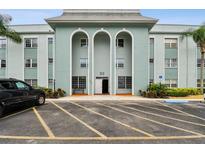 Light blue condo building featuring covered parking and landscaping at 701 Poinsettia Rd # 322, Belleair, FL 33756