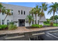 Charming condo building featuring lush landscaping and covered entryway to units on the second floor at 720 Lyndhurst St # 1101, Dunedin, FL 34698