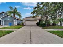 Well-maintained single-story home featuring a large driveway, mature trees, and lush landscaping at 7603 Wood Violet Dr, Gibsonton, FL 33534