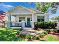 Charming single-Gathering home with a welcoming front porch, blue front door and well-manicured landscaping at 910 E Crenshaw St, Tampa, FL 33604