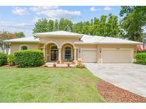 Beautiful tan single-story home with a manicured lawn, clean landscaping, and a white roof at 17906 Loretta Ln, Lutz, FL 33548